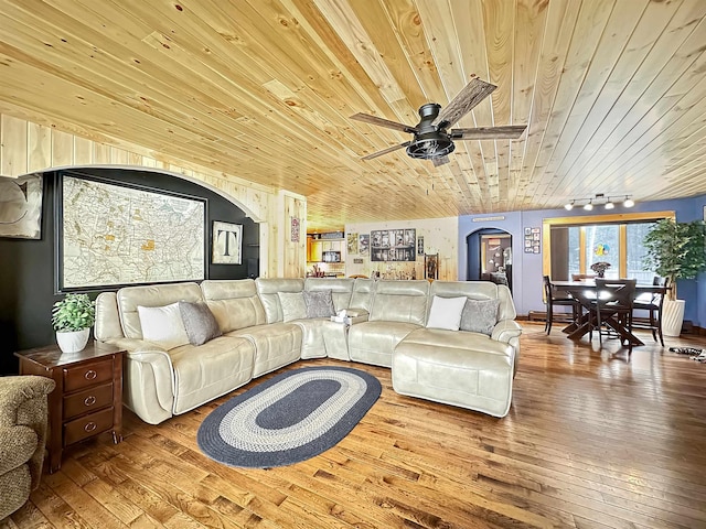 living area with arched walkways, ceiling fan, track lighting, wood finished floors, and wooden ceiling