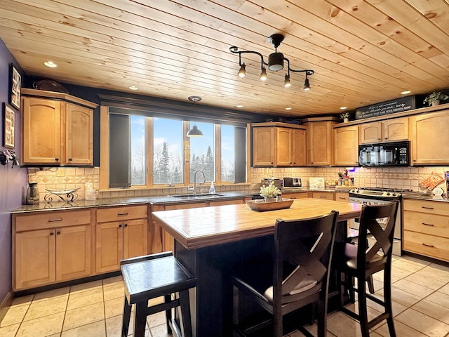 kitchen with gas range, a kitchen island, a kitchen breakfast bar, black microwave, and a sink