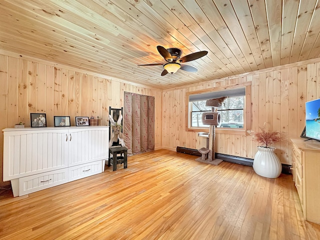 interior space featuring light wood finished floors, a baseboard radiator, a ceiling fan, wood walls, and wooden ceiling