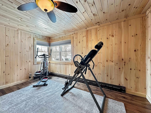 workout area featuring wooden walls, wooden ceiling, dark wood finished floors, and baseboards