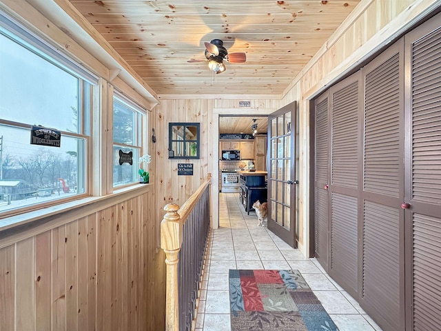 corridor featuring wood ceiling, wooden walls, and light tile patterned floors