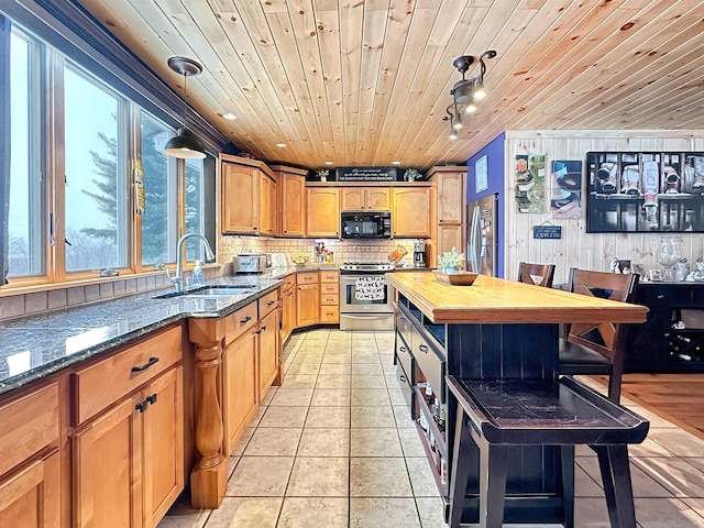 kitchen featuring decorative light fixtures, appliances with stainless steel finishes, wood ceiling, a sink, and dark stone countertops