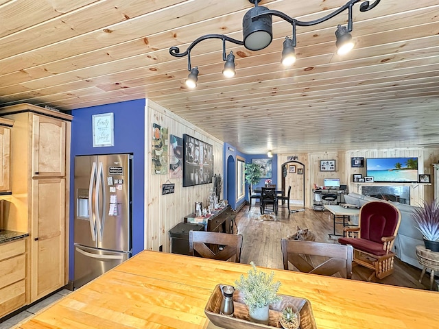 kitchen with wood finished floors, wood ceiling, open floor plan, stainless steel fridge with ice dispenser, and light brown cabinetry