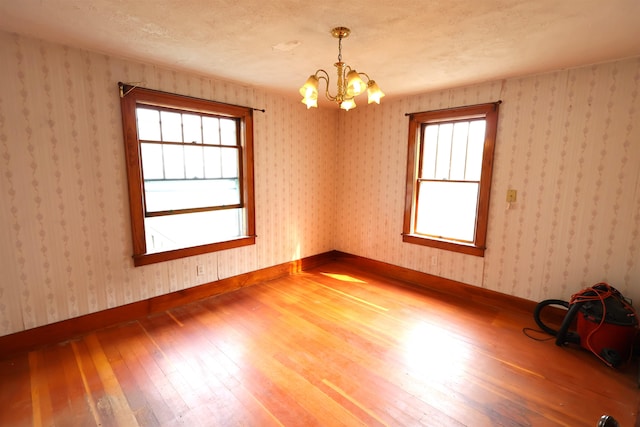 unfurnished room with an inviting chandelier and hardwood / wood-style flooring