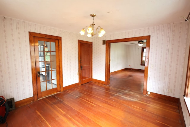 spare room featuring ceiling fan with notable chandelier and wood-type flooring