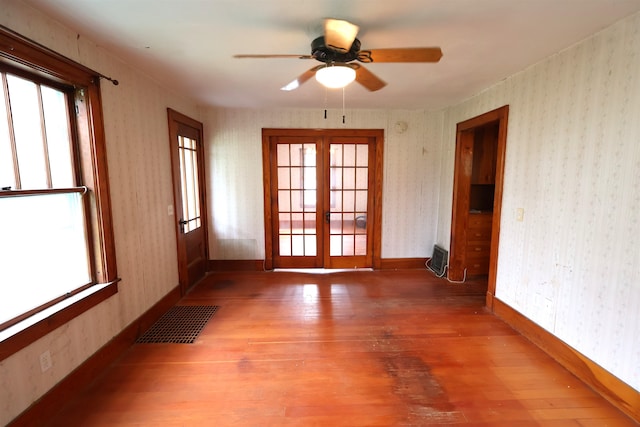 spare room featuring ceiling fan, french doors, a wealth of natural light, and wood-type flooring