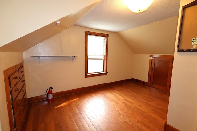 bonus room featuring a textured ceiling, vaulted ceiling, and wood-type flooring