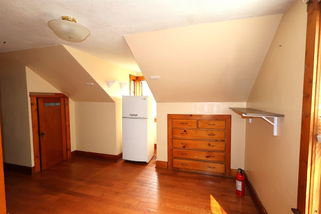 bonus room with a textured ceiling, vaulted ceiling, and dark hardwood / wood-style flooring