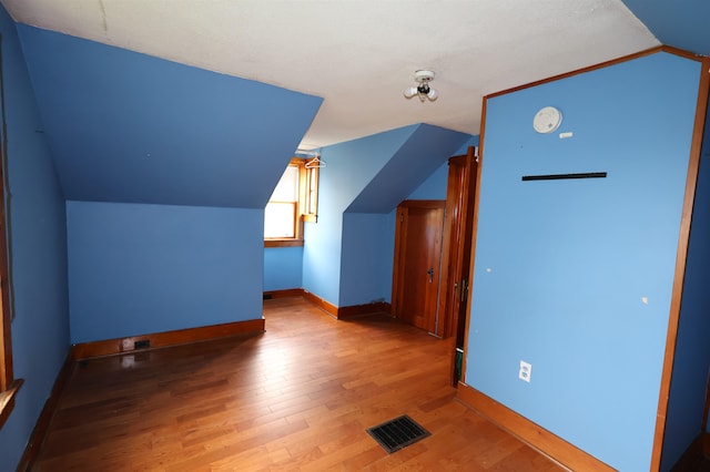 additional living space with vaulted ceiling and hardwood / wood-style flooring