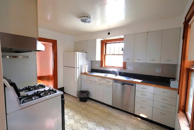 kitchen featuring sink, wall chimney exhaust hood, white appliances, light tile patterned floors, and white cabinets