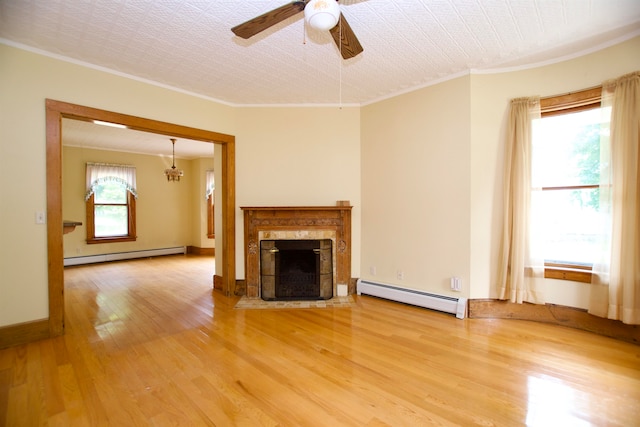 unfurnished living room featuring a baseboard radiator, a wealth of natural light, and light hardwood / wood-style flooring