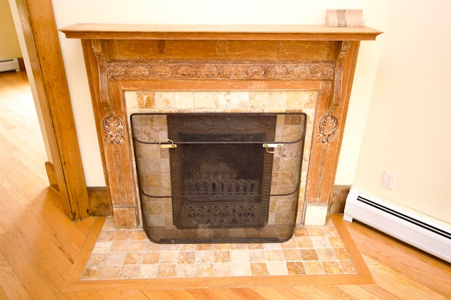 interior details featuring hardwood / wood-style flooring, baseboard heating, and a tiled fireplace