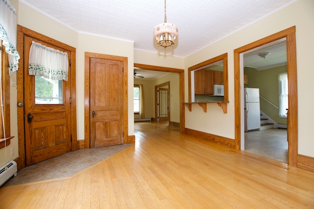 foyer with a notable chandelier, light wood-type flooring, a baseboard heating unit, a textured ceiling, and crown molding