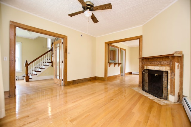 unfurnished living room featuring light hardwood / wood-style floors, ornamental molding, a baseboard radiator, a high end fireplace, and ceiling fan