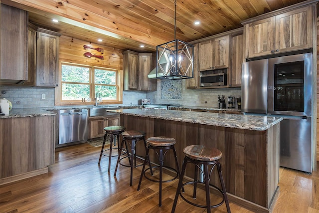 kitchen featuring dark stone counters, a center island, stainless steel appliances, and light hardwood / wood-style flooring