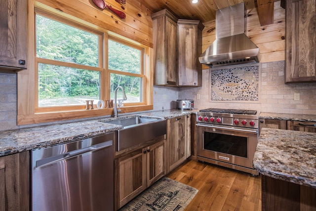 kitchen featuring light hardwood / wood-style flooring, plenty of natural light, extractor fan, appliances with stainless steel finishes, and light stone countertops
