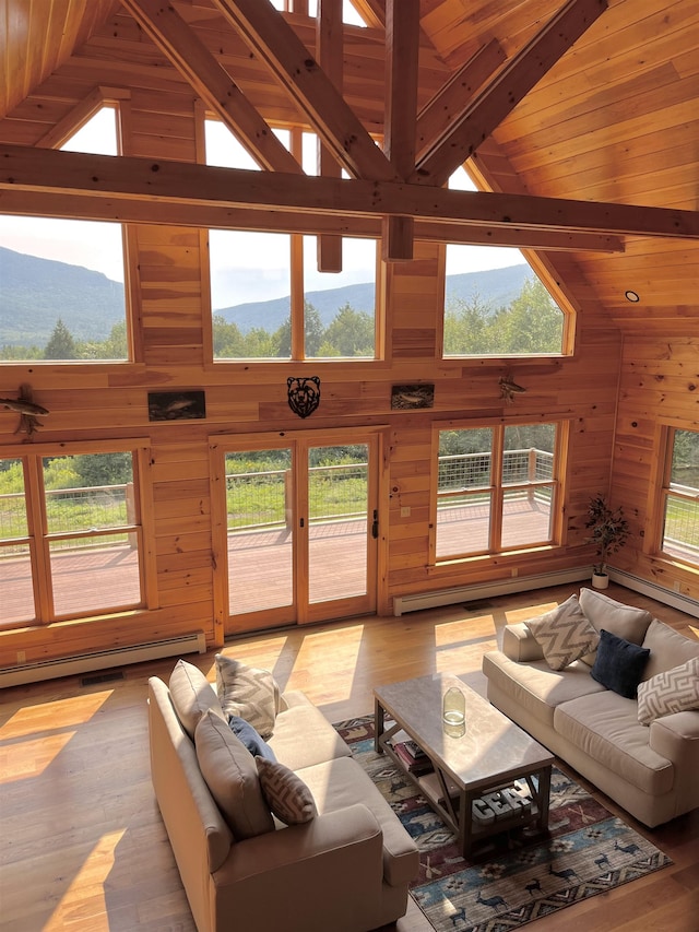 unfurnished living room with wooden walls, light wood-type flooring, high vaulted ceiling, and a healthy amount of sunlight