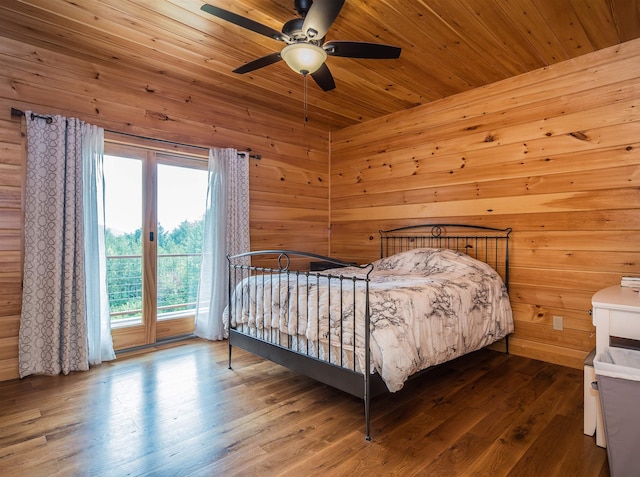 bedroom with ceiling fan, wood walls, and hardwood / wood-style floors