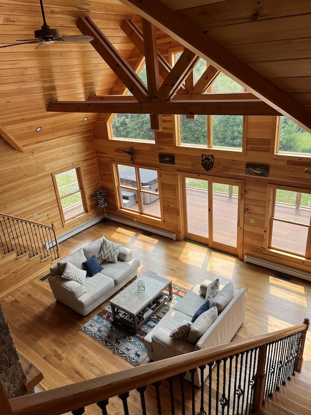 living room with high vaulted ceiling, a healthy amount of sunlight, and wood walls
