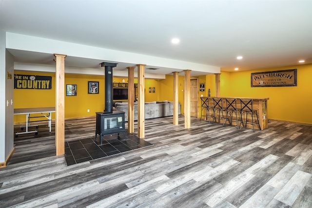 living room with a wood stove, indoor bar, and hardwood / wood-style floors