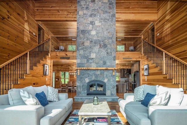 living room with wooden walls, a towering ceiling, and hardwood / wood-style floors