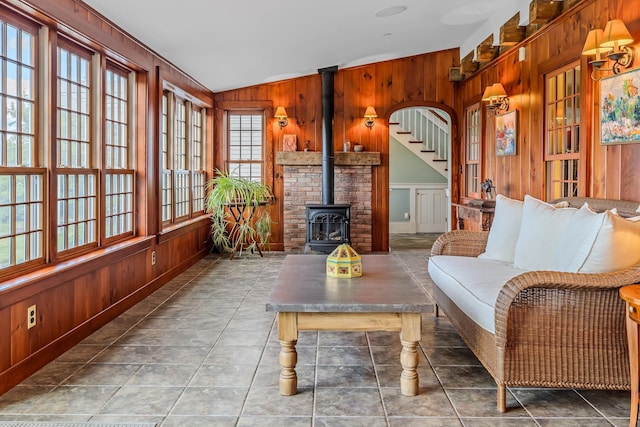interior space featuring wood walls, a wood stove, vaulted ceiling, and tile patterned floors