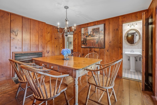 dining space featuring hardwood / wood-style floors, wooden walls, a fireplace, and an inviting chandelier