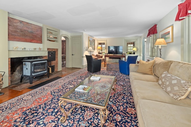 living room with arched walkways and a wood stove
