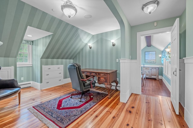 office space with baseboard heating, vaulted ceiling, wallpapered walls, wainscoting, and wood-type flooring