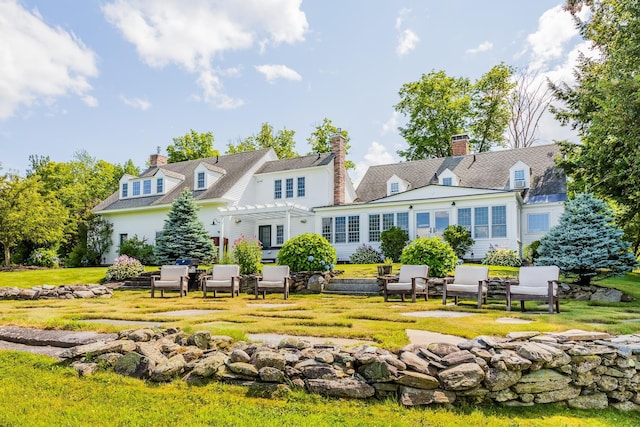 back of property featuring a yard, a chimney, and a pergola