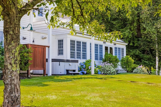 back of property featuring a hot tub and a lawn