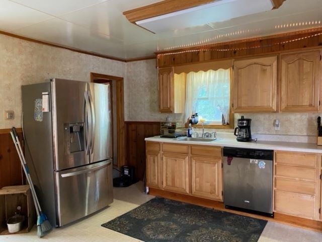 kitchen featuring stainless steel appliances, wood walls, and sink