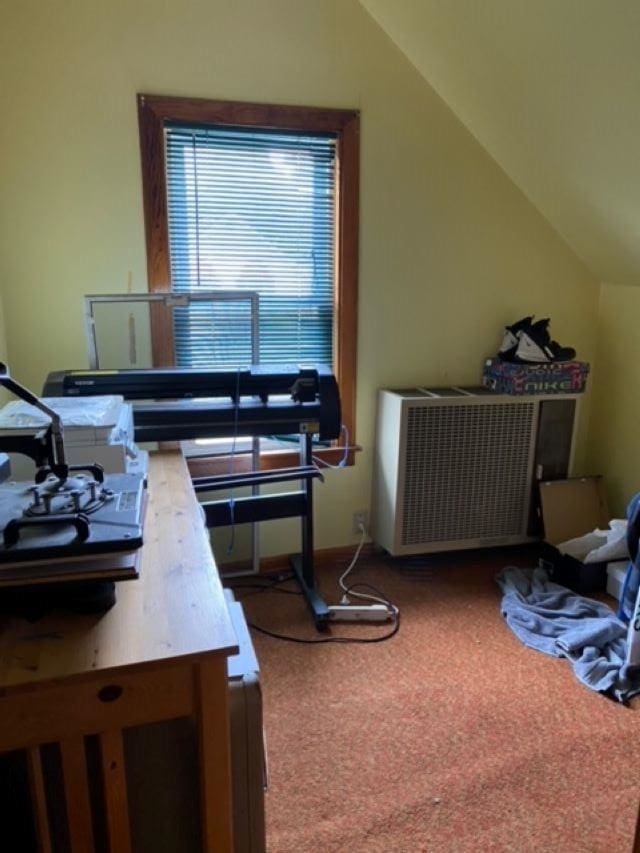 carpeted home office featuring vaulted ceiling