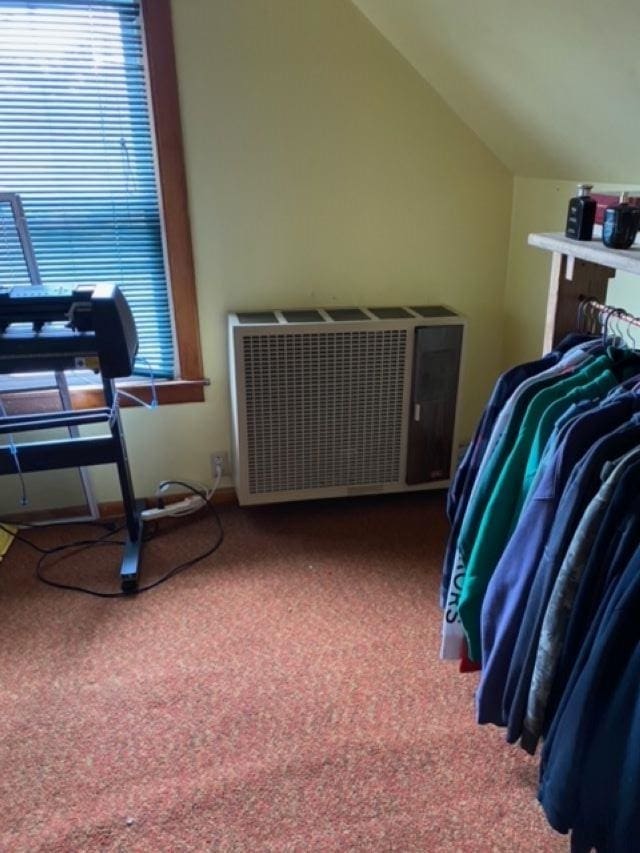 bedroom with radiator heating unit, lofted ceiling, and carpet