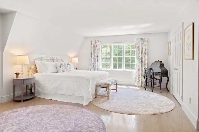 bedroom featuring lofted ceiling, wood finished floors, and baseboards