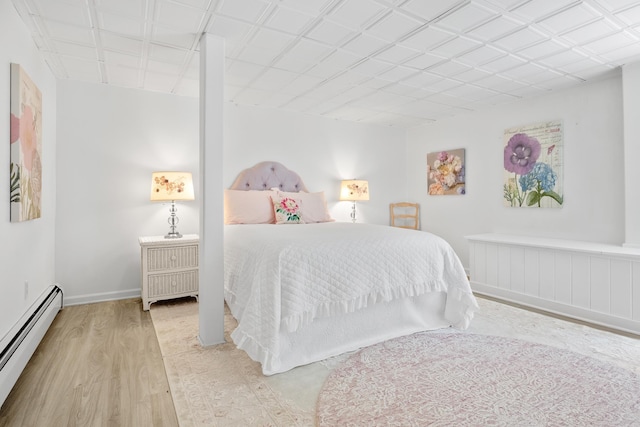 bedroom featuring baseboards, wood finished floors, and a baseboard heating unit