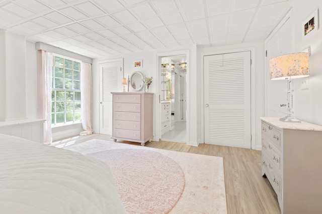 bedroom with connected bathroom and light wood finished floors