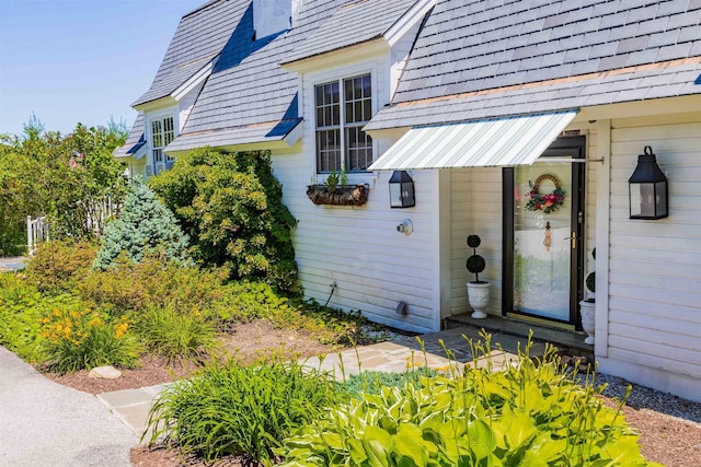 view of exterior entry featuring a high end roof