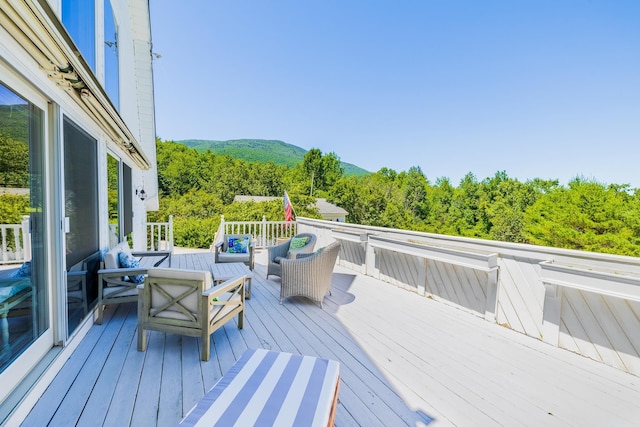 deck with outdoor lounge area and a wooded view