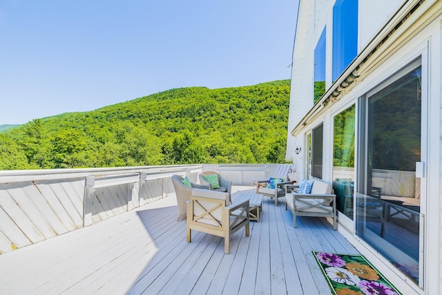 wooden deck with an outdoor hangout area and a forest view