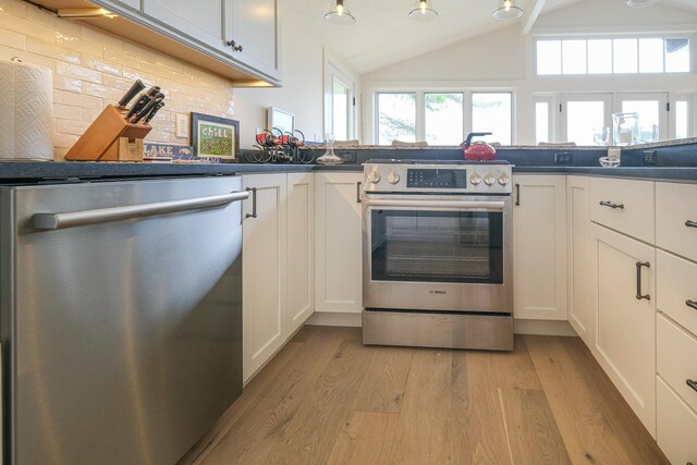 kitchen featuring stainless steel appliances, tasteful backsplash, light hardwood / wood-style flooring, lofted ceiling, and white cabinets