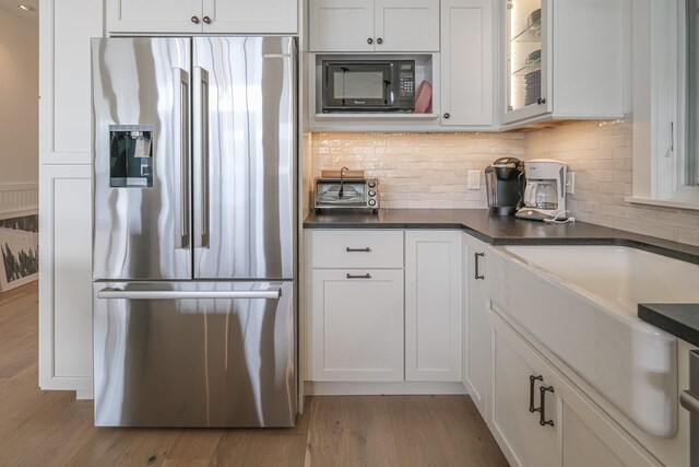 kitchen with stainless steel fridge with ice dispenser, light hardwood / wood-style flooring, white cabinetry, and tasteful backsplash