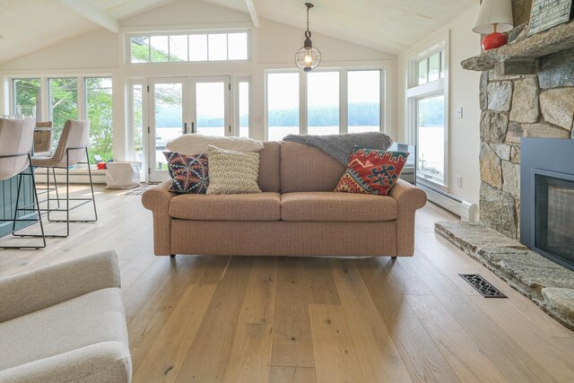 living room featuring beam ceiling, a wealth of natural light, and light hardwood / wood-style flooring