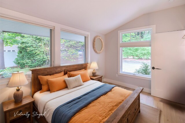 bedroom featuring baseboard heating, vaulted ceiling with beams, and light hardwood / wood-style flooring