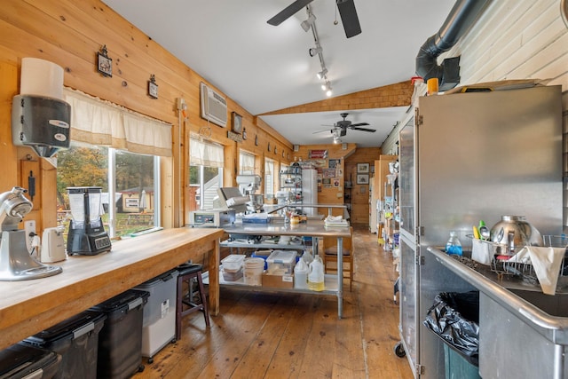 kitchen featuring butcher block counters, a ceiling fan, vaulted ceiling, wooden walls, and hardwood / wood-style floors