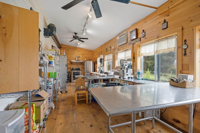 kitchen featuring vaulted ceiling, hardwood / wood-style floors, stainless steel countertops, and wooden walls