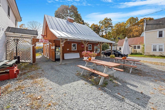 exterior space with metal roof, a standing seam roof, a chimney, and an outdoor structure