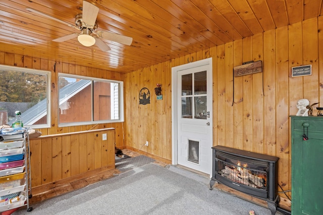 unfurnished living room featuring wood walls, carpet flooring, wood ceiling, and a ceiling fan