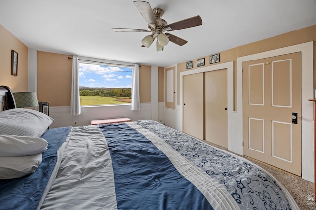 bedroom featuring a wainscoted wall, ceiling fan, and a closet