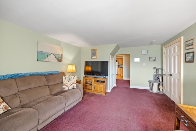 living area featuring dark colored carpet and baseboards